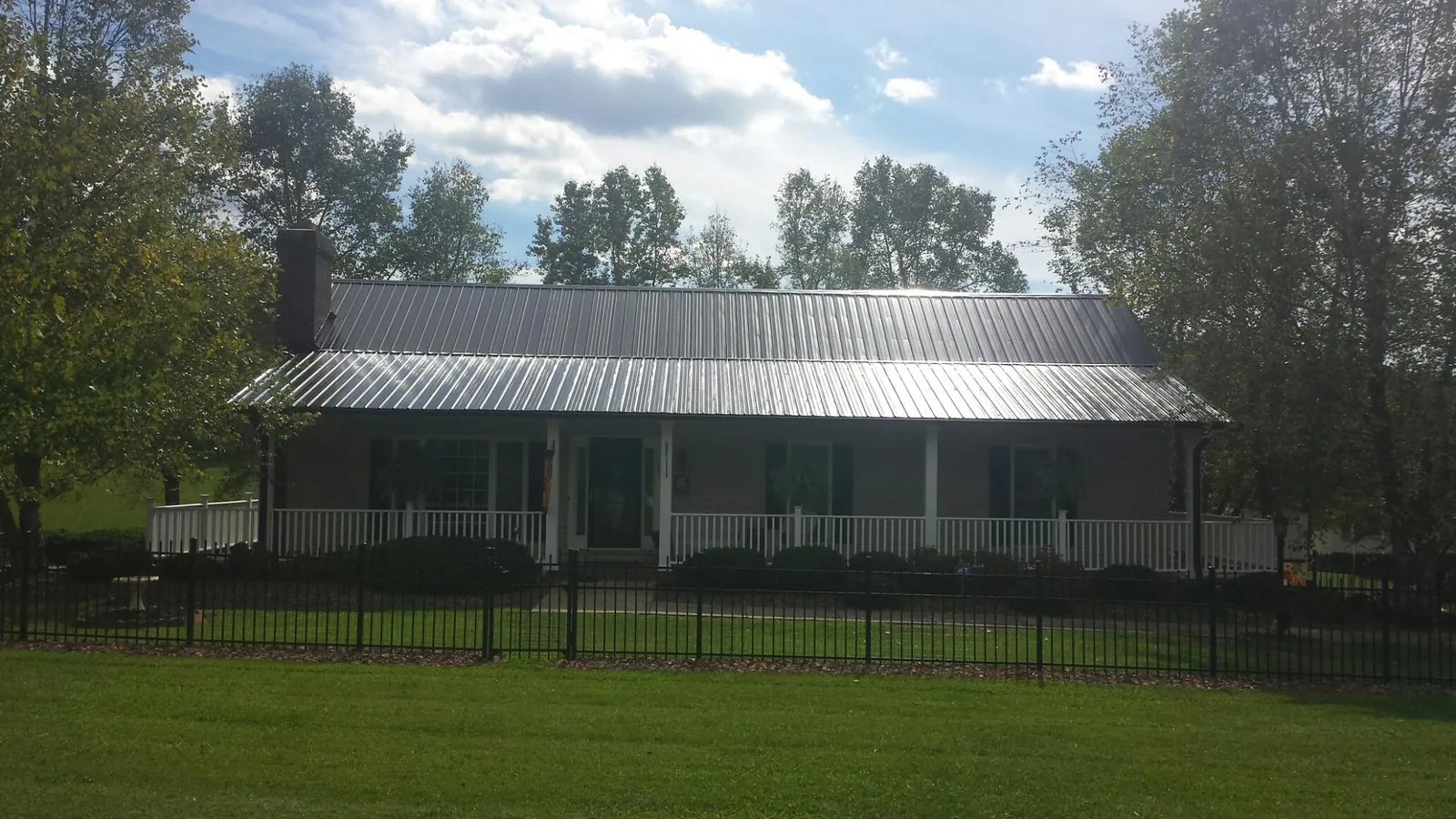 Gray metal roof on a brick ranch with a full width front porch — Gutter Guard Installation work by our crew in Shohola