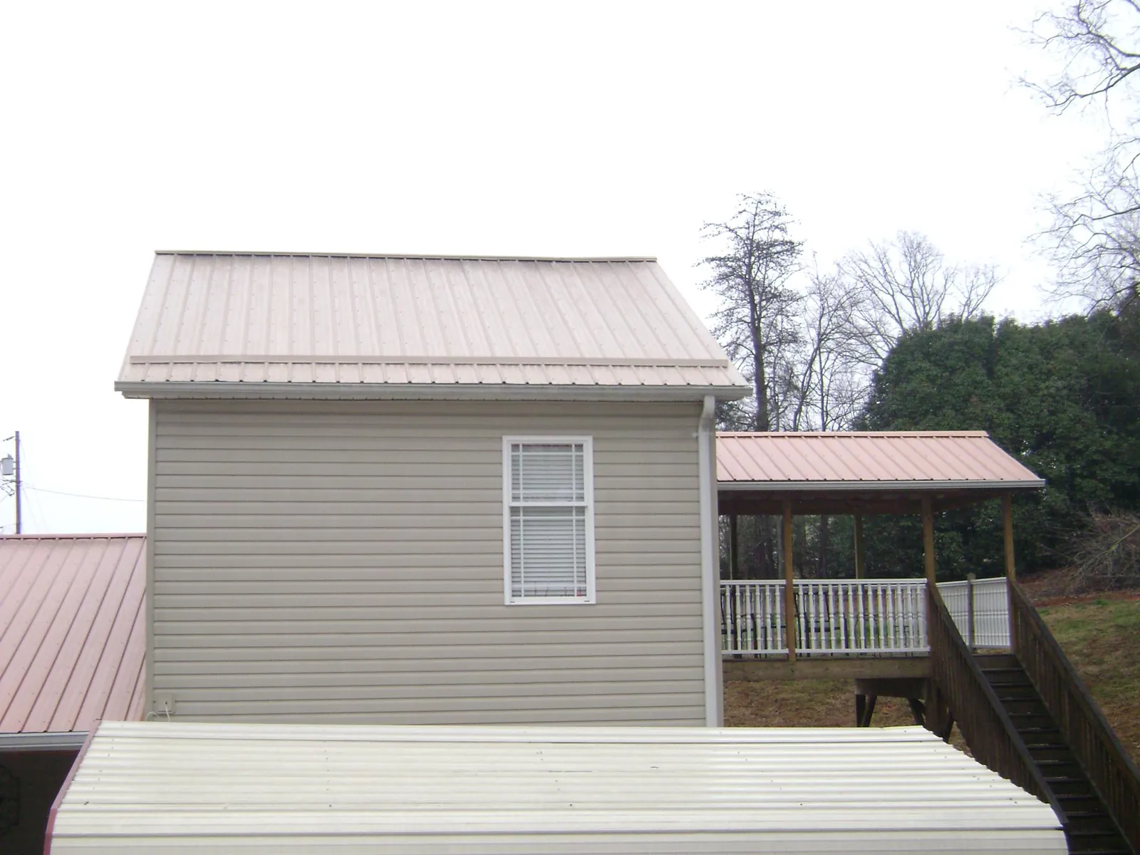 Tan metal roofs on a two story addition and attached porch, from a Roof Replacement job in Shohola