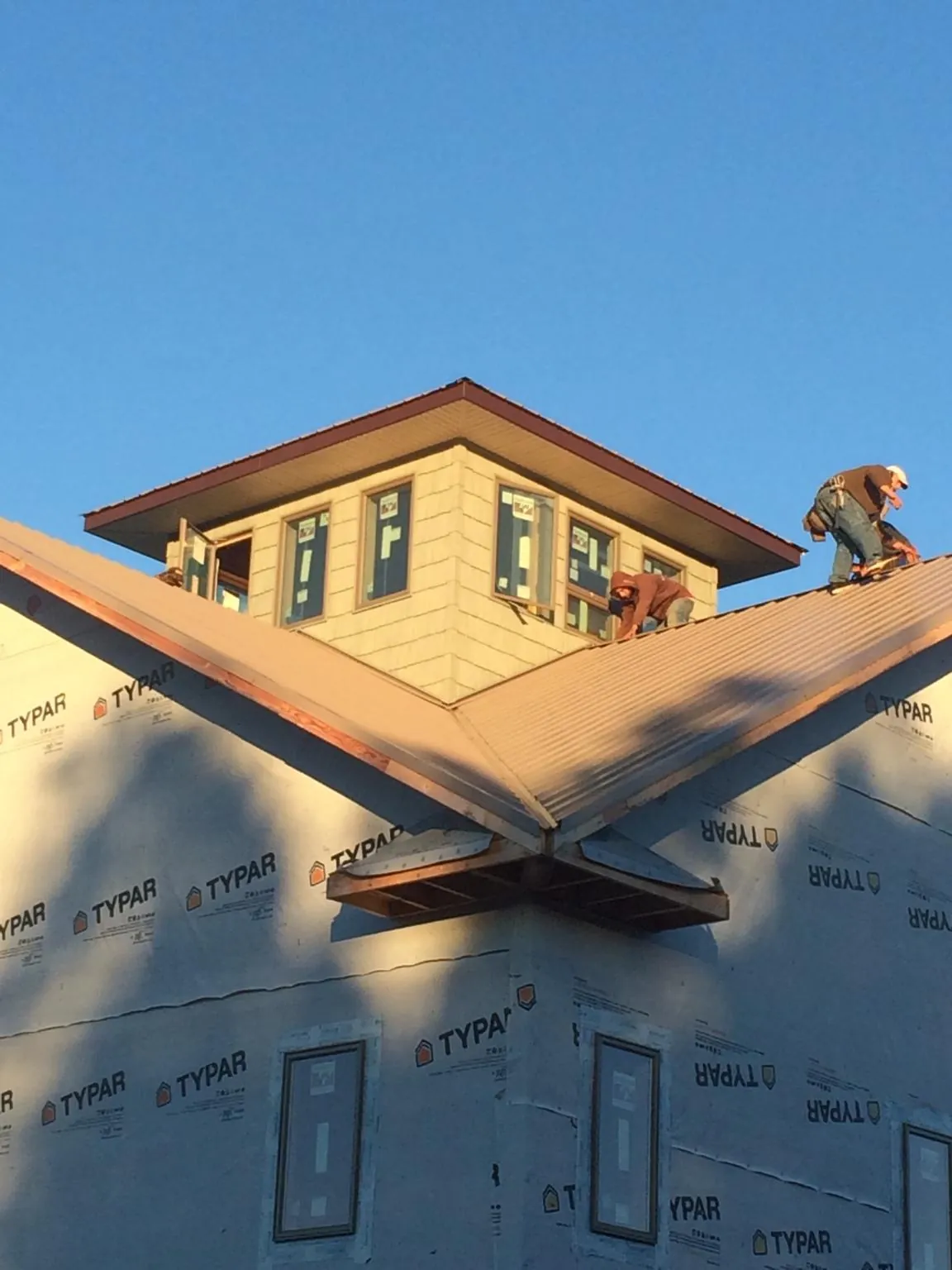 Roofers working around a rooftop cupola on a new metal roof at sunset — Roof Waterproofing in Shohola by Roofing Brothers